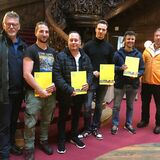 Gruppe der Absolventen und zwei Prüfer vor einer wunderschönen gedrechselten Holzstiege